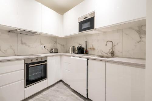 une cuisine blanche avec des armoires et des appareils blancs dans l'établissement Appartement des Colombes - Welkeys, à Courbevoie
