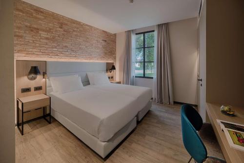 a bedroom with a white bed and a blue chair at NH Collection Murano Villa in Murano