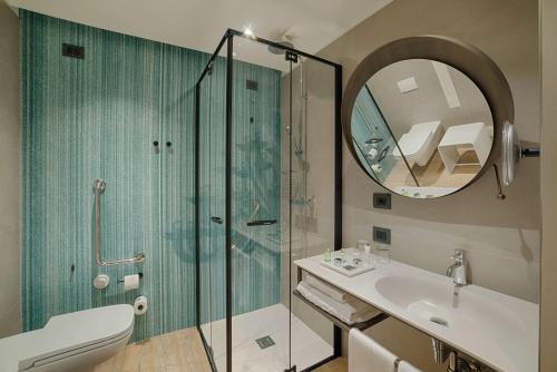 a bathroom with a shower and a sink and a mirror at NH Collection Murano Villa in Murano