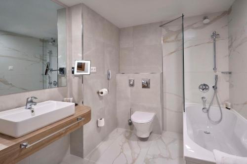 a bathroom with a sink and a toilet and a shower at Radisson Hotel Plovdiv in Plovdiv