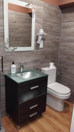 a bathroom with a sink and a toilet and a mirror at Pensión La Estación in Sarria