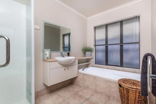 ein Badezimmer mit einer Badewanne, einem Waschbecken und einer Badewanne in der Unterkunft Stunning Family Home in Auckland