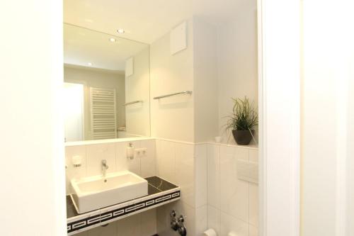 a white bathroom with a sink and a mirror at strandnah, Ferienwohnung mit Sauna- und Schwimmbadnutzung - Strandresidenz Baabe FeWo1-29 in Baabe