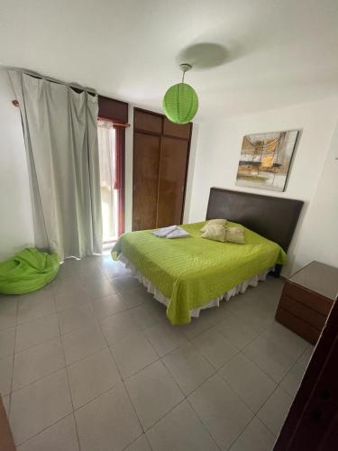 a bedroom with a bed with a green blanket on it at Chacabuco 36 in Córdoba