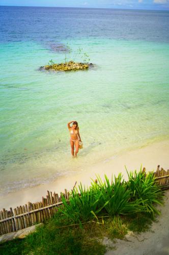 a woman walking in the water on a beach at Casa Tinti in Tintipan Island