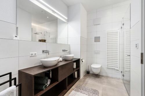 a white bathroom with two sinks and a toilet at Premium 24h SmartApart Modern mit Smarthome zentral-Welcome drink inkl in Tettnang
