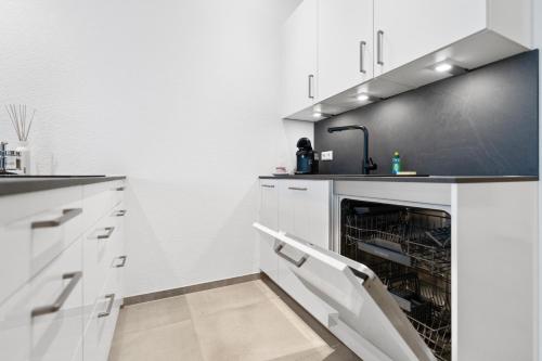 a kitchen with white cabinets and a dishwasher at Premium 24h SmartApart Modern mit Smarthome zentral-Welcome drink inkl in Tettnang