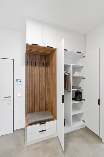 a closet with white cabinets and a wooden door at Premium 24h SmartApart Modern mit Smarthome zentral-Welcome drink inkl in Tettnang
