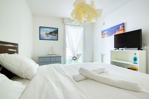 - une chambre blanche avec un grand lit blanc et une télévision dans l'établissement Super T2 Climatisé avec Balcon à pied plage Catalan, à Marseille