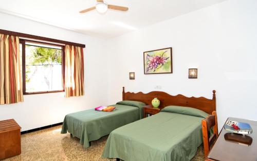 1 dormitorio con 2 camas y ventana en Hostal La Ceiba, en Cala d´Or