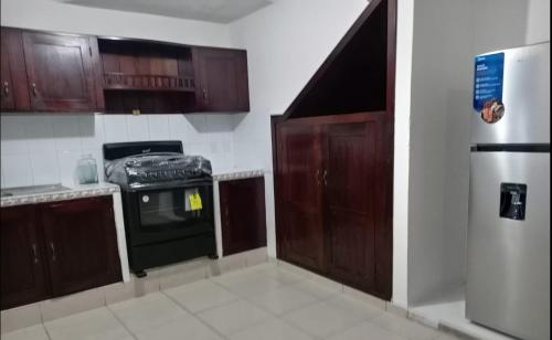 uma cozinha com armários de madeira, um fogão e um frigorífico em A 5 MINUTOS DEL CORAZON DE TACNA em Tacna