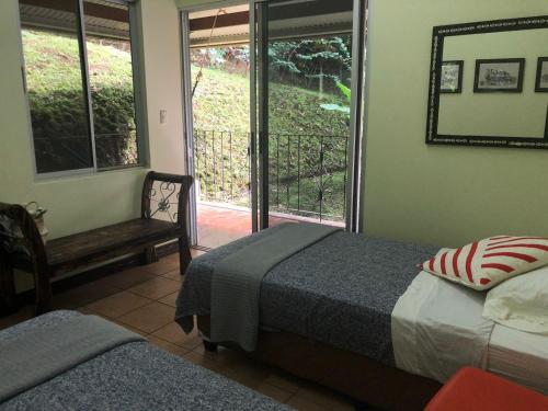 a bedroom with two beds and a chair and a window at SERENITY BY NATURE in Carrillos