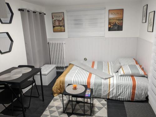 a small bedroom with a bed and a table at Studio Volta Garden proche du tram in Tours