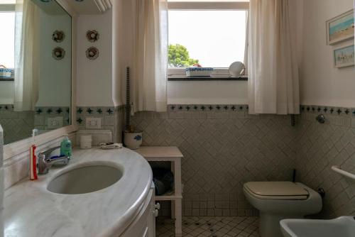 Un baño con lavabo, inodoro y ventana. en Beautiful Villa with View in the heart of Capri, en Capri
