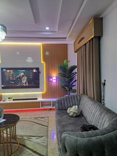 uma sala de estar com um sofá e uma televisão em GRACEPOINT APARTMENT em Rubuchi