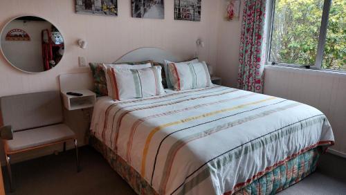 a bedroom with a bed and a chair and a mirror at Bed and Breakfast Happy Home Taupo Accommodation in Taupo