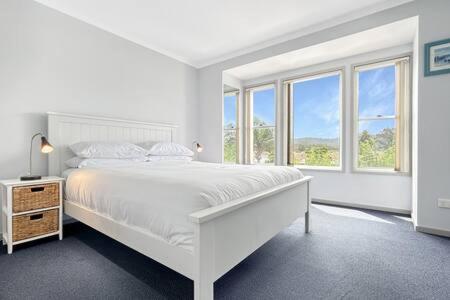 1 dormitorio blanco con 1 cama grande y ventanas en 3-Bed with Alfresco Dining & Pool in Batemans Bay, en Batemans Bay
