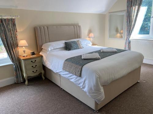 a bedroom with a large bed and a nightstand with two lamps at Silhouette Cottage in Coleford