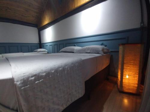 Casa da Lagoa - Gasthaus Pomerode في بوميرودي: غرفة نوم بسرير كبير مع شراشف بيضاء
