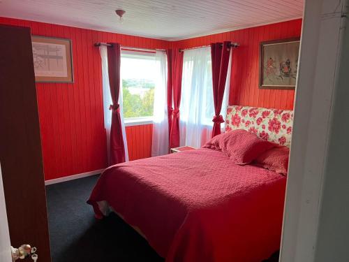 a red bedroom with a bed and a window at Arenas de Ancud in Ancud
