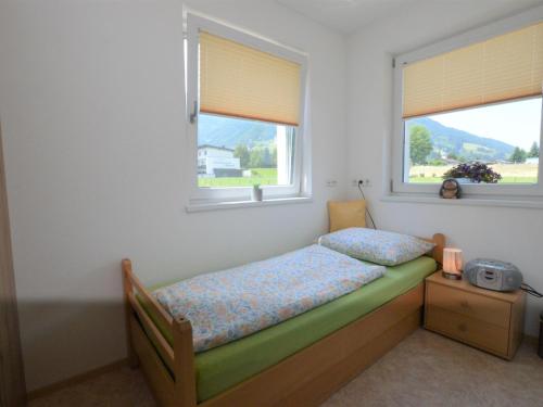 a small bedroom with a bed and two windows at Karo in Mittersill