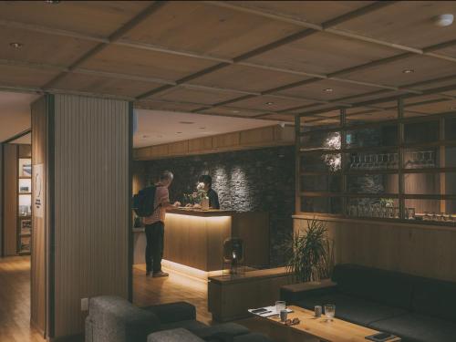 a man standing at a bar in a restaurant at Chalet Shiga in Yamanouchi