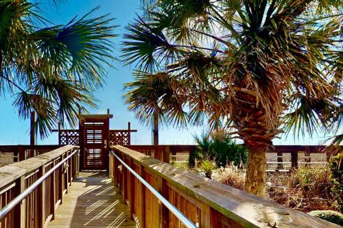 a wooden boardwalk with palm trees on the beach at Casa Al Mare in Carolina Beach
