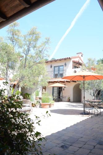 a patio with tables and an umbrella and a building at Su Nido Inn in Ojai