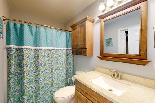 a bathroom with a toilet and a sink and a mirror at Three Sea in Carolina Beach