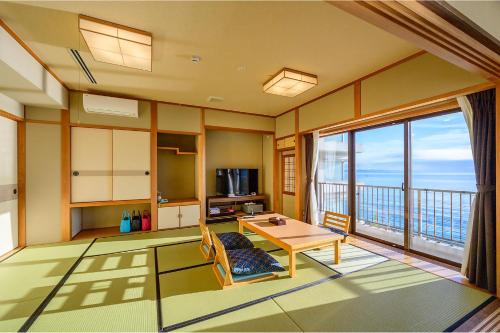 a living room with a table and a balcony at Ooedo Onsen Monogatari Beppu Seifu in Beppu