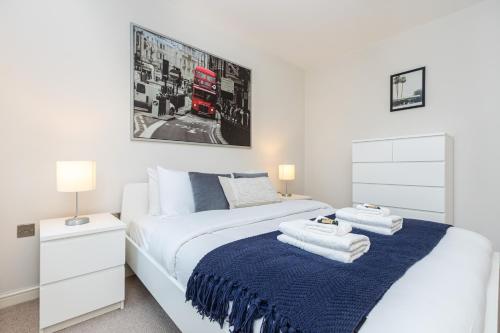 een slaapkamer met een wit bed en een blauwe deken bij Hidden Gem 2BR flat wBalcony near Surrey Quays in Londen