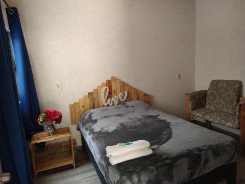 馬利納爾科的住宿－Departamento cómodo y céntrico en Malinalco.，一间卧室配有一张床、一把椅子和鲜花