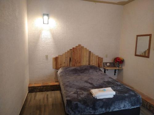 ein Schlafzimmer mit einem Bett mit einem Kopfteil aus Holz in der Unterkunft Departamento cómodo y céntrico en Malinalco. in Malinalco