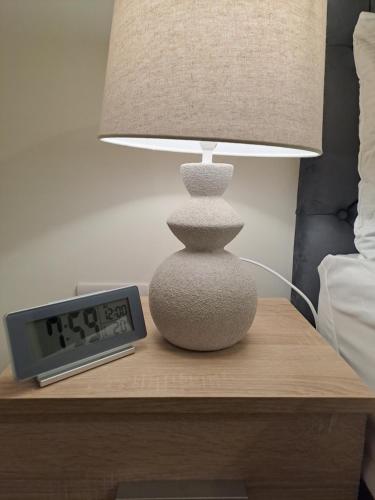 a lamp and an alarm clock on a table next to a bed at Cozy bedroom in Lucan, Dublin in Dublin