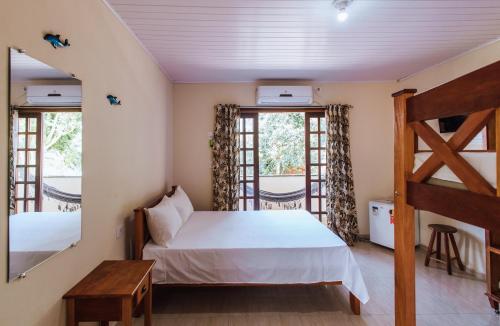 a bedroom with a bed and two windows at pousada formibela in Ilhabela