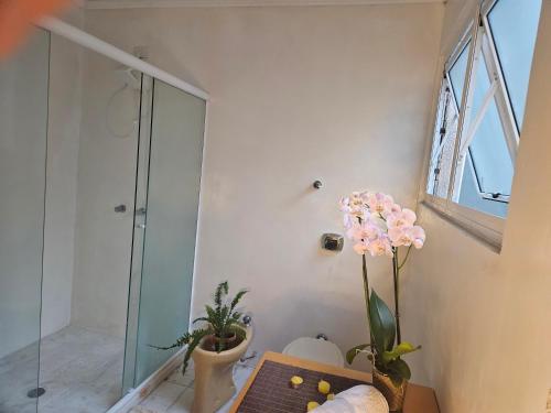 uma casa de banho com um chuveiro e um vaso de flores em Espaço Semente Poa Violeta em Porto Alegre