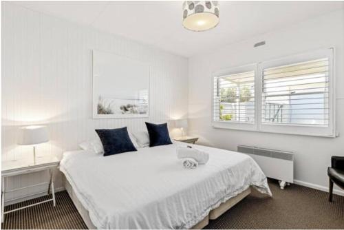 1 dormitorio blanco con 1 cama grande y 2 ventanas en Sorrento Beach Cottages No. 2 - in the heart of Sorrento, en Sorrento