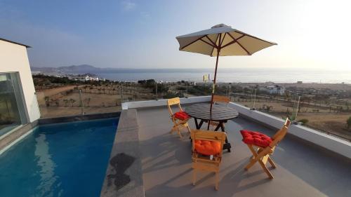 - un balcon avec une table, des chaises et un parasol dans l'établissement CASA DE PLAYA Todo el año, à Punta Negra