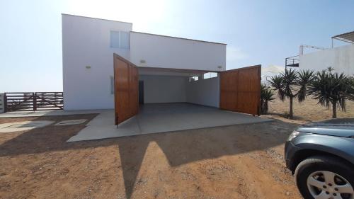 a white house with a car parked in front of it at CASA DE PLAYA Durante todo el año in Punta Negra