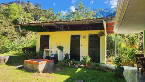 a yellow house with black doors in a yard at Hospedajes Richie Eco Camp in Providencia