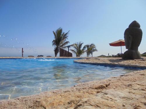 a swimming pool on a beach with palm trees at Balihai Bungalows in Canoas De Punta Sal