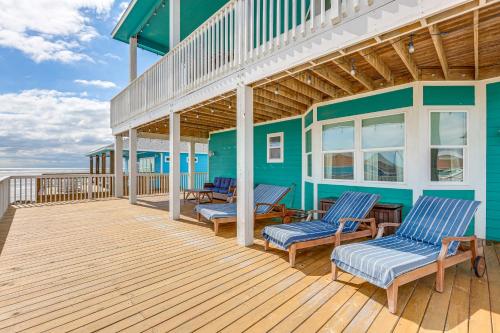 a deck with blue chairs and a blue house at Footprints in the Sand - Luxe Freeport Home! in Freeport