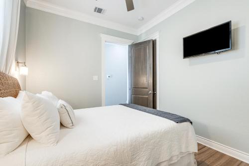 a bedroom with a white bed with a flat screen tv at Footprints in the Sand - Luxe Freeport Home! in Freeport