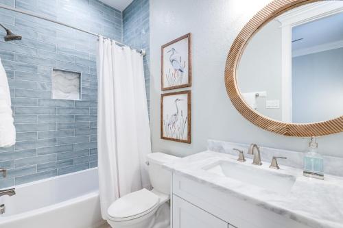 a bathroom with a sink and a toilet and a mirror at Footprints in the Sand - Luxe Freeport Home! in Freeport