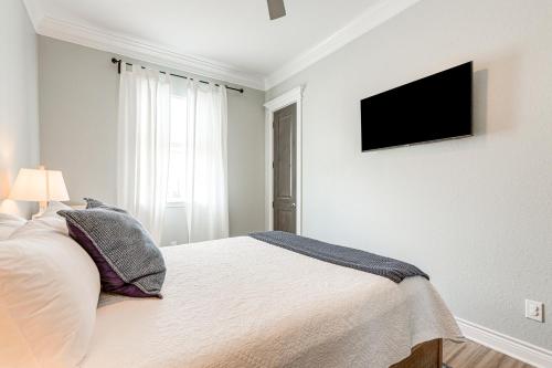 a white bedroom with a bed and a flat screen tv at Footprints in the Sand - Luxe Freeport Home! in Freeport