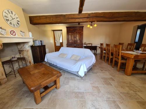 una camera con letto, tavolo e orologio di Charmant Gîte en Brenne avec Jardin, Piscine Partagée et Proximité Sentiers de Randonnée - FR-1-591-99 a Prissac
