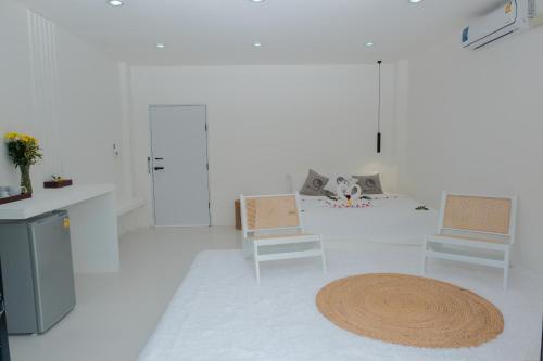 a white living room with two chairs and a rug at MoonE in Ban Karon