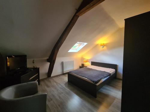 a bedroom with a bed and a television in a attic at Charmante maison avec jardin, au cœur du Berry, proche rivière et randonnées - FR-1-591-57 in Chasseneuil