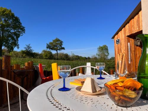 a white table with wine glasses and a bowl of bread at Gîte "Tout Inclus" en Campagne Berrichonne avec Terrasse & Parking Privé - FR-1-591-419 in Briantes