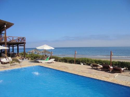 a swimming pool next to a beach with the ocean at Balihai Bungalows in Canoas De Punta Sal